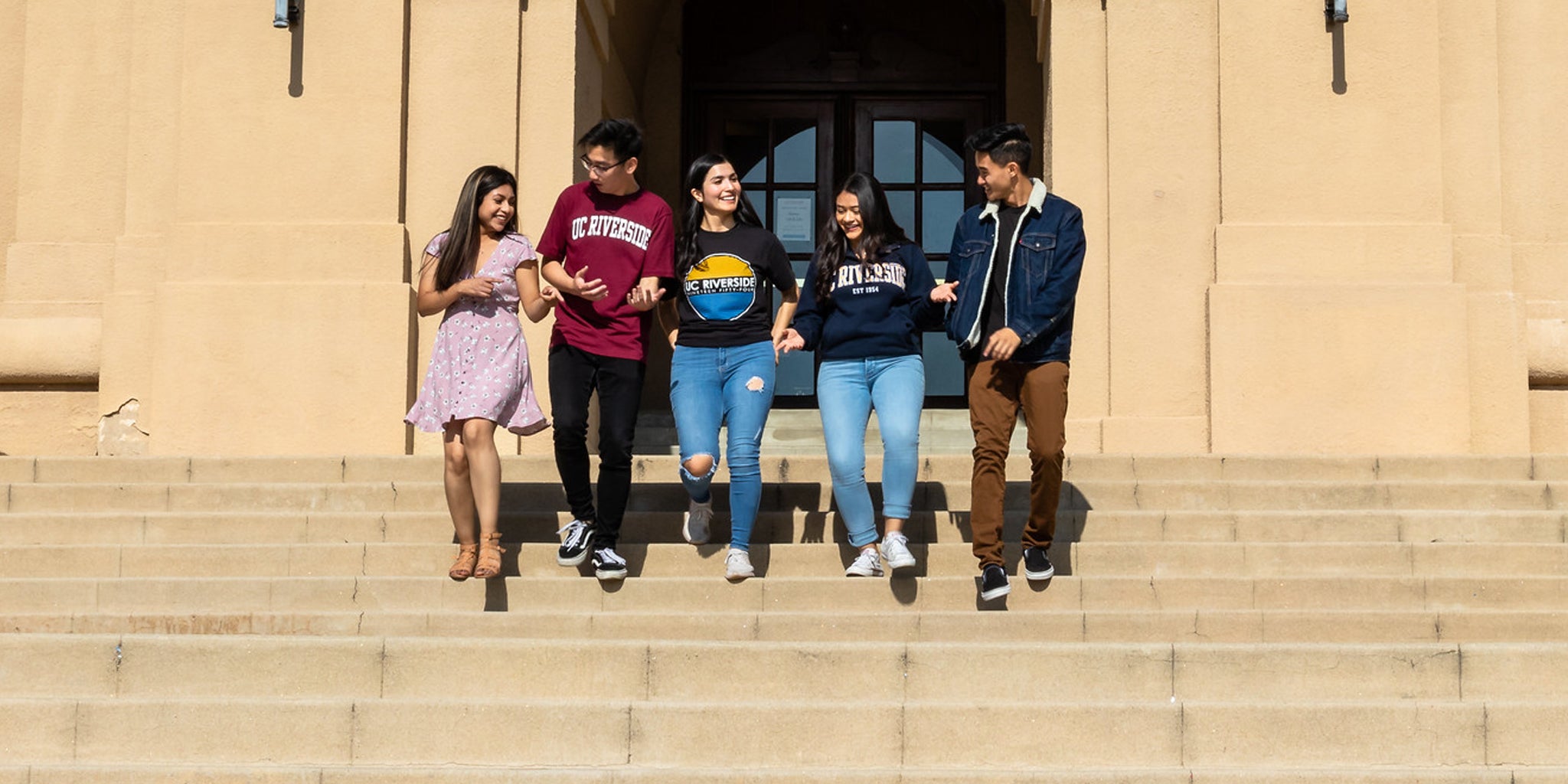 A group of UCR students talk as they walk down the stairs of the A. Gary Anderson Graduate School of Management building.