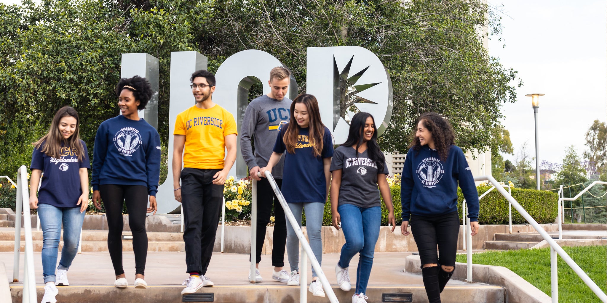 A group of UCR students talk as they walk down the steps in front of the UCR letter sculpture.