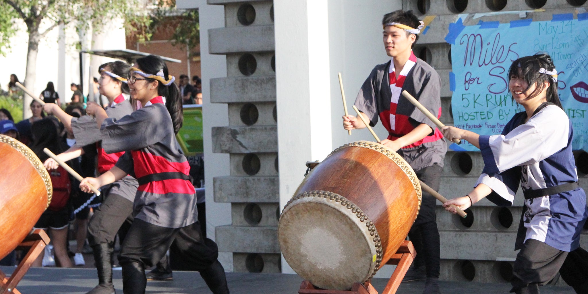 Students play taiko drums during a campus event.