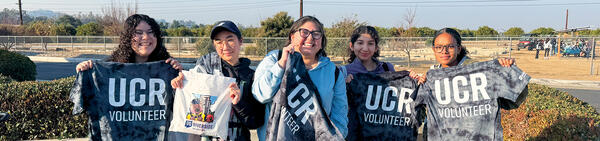 Students holding up UCR Volunteer T-shirts