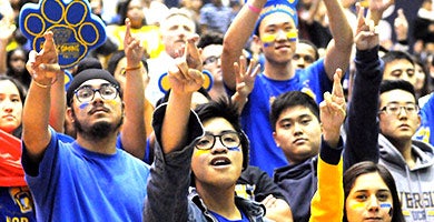 A group of UCR students dressed in blue and gold cheer on the Highlanders. 