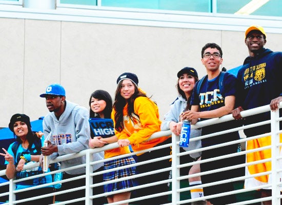 A group of UC Riverside students pose on the railing of the Highlander Union Building upper patio.
