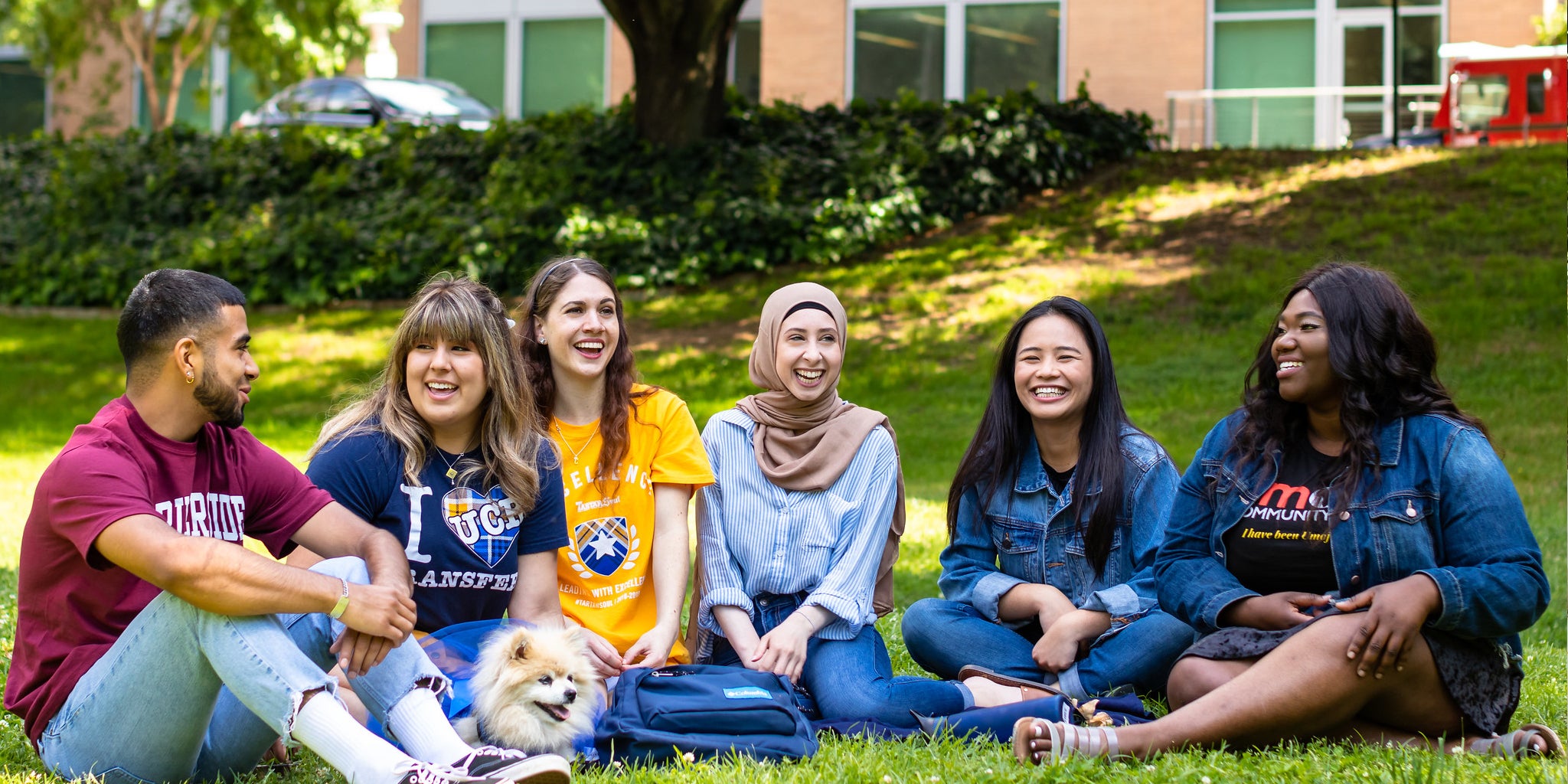 A group of UCR students sit together on a campus lawn.